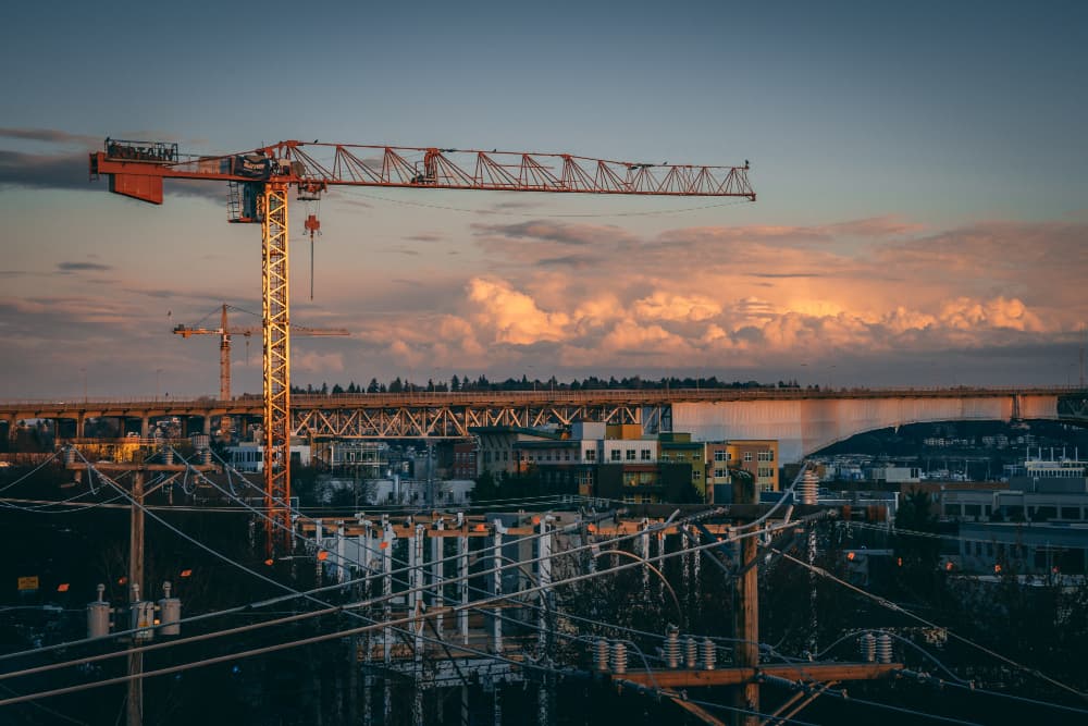 A tower crane over an active construction site at dusk
