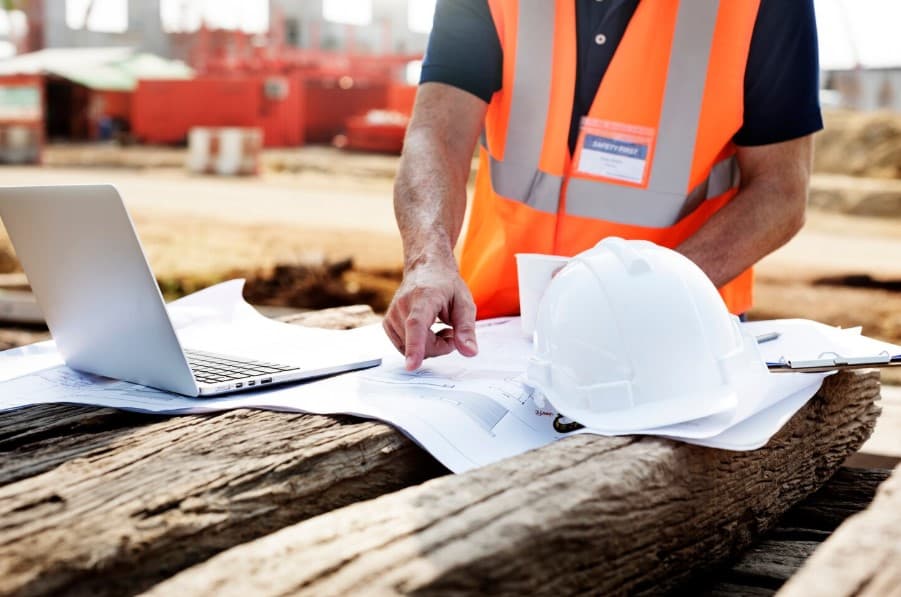 Drawings, a laptop and a hard hat on a working desk